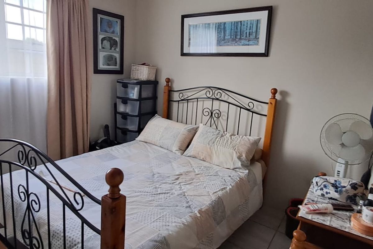 A functional bedroom featuring tiled flooring and a window with security bars, providing a comfortable and practical living space.