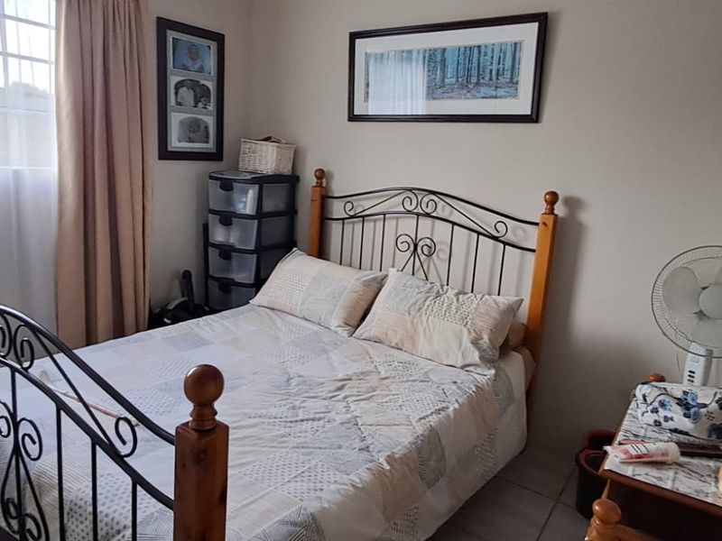 A functional bedroom featuring tiled flooring and a window with security bars, providing a comfortable and practical living space.