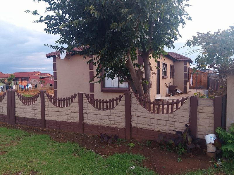 A single-story residential house featuring a tiled roof and a decorative precast concrete boundary wall with a front garden area.