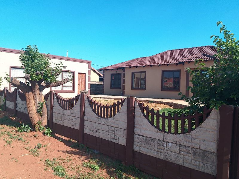 Front view of a single-story residential house featuring a tiled roof, aluminium window frames, and a decorative precast concrete boundary wall.