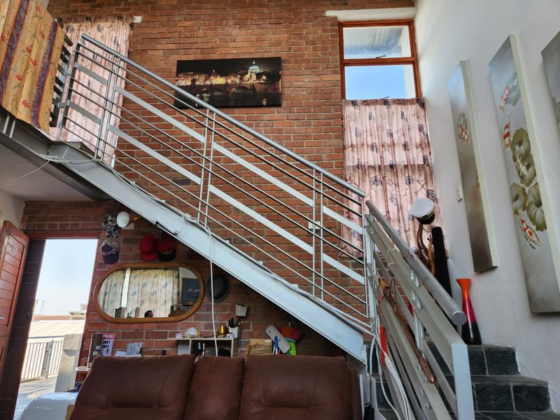 Living area featuring an industrial-style exposed brick wall and a prominent metal staircase with a modern balustrade.