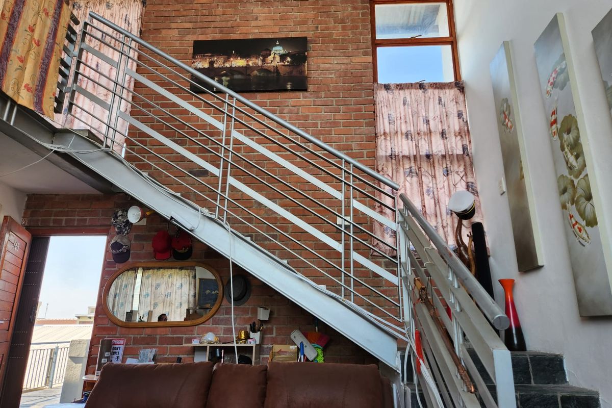 Living area featuring an industrial-style exposed brick wall and a prominent metal staircase with a modern balustrade.