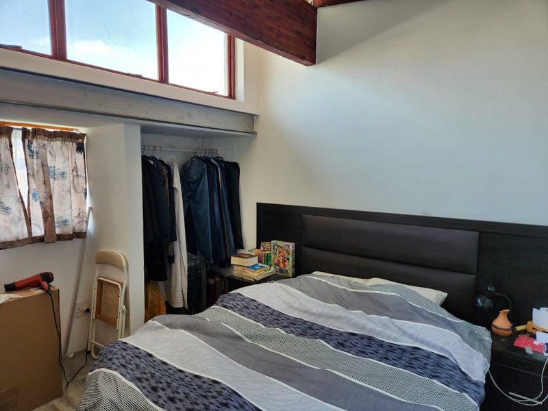 A bedroom featuring an exposed timber beam, clerestory windows for natural light, and a built-in wardrobe area.