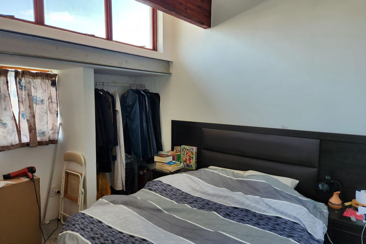 A bedroom featuring an exposed timber beam, clerestory windows for natural light, and a built-in wardrobe area.