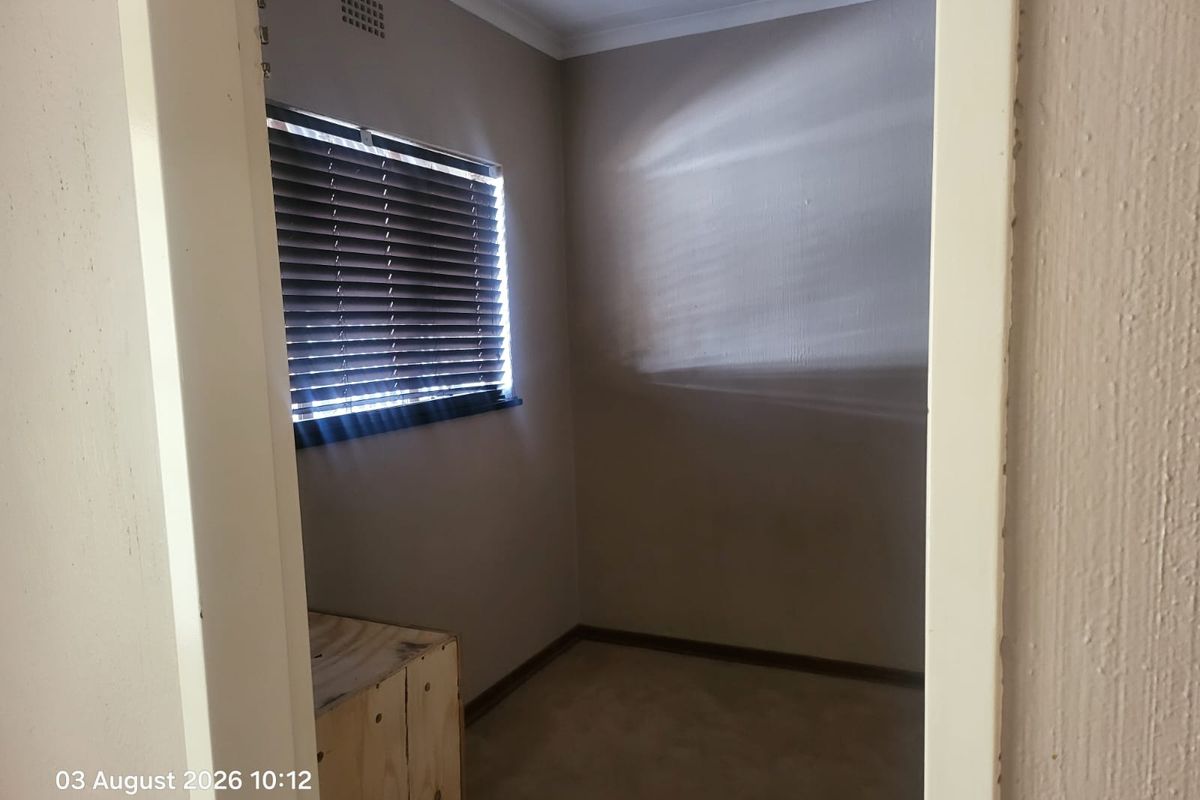 A small, empty bedroom featuring neutral wall paint and venetian blinds, offering a blank canvas for potential bedroom or home office use.