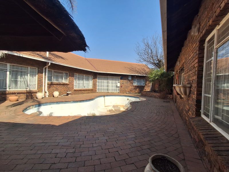Outdoor pool area featuring a face brick exterior, paved patio, and a swimming pool requiring maintenance and restoration.