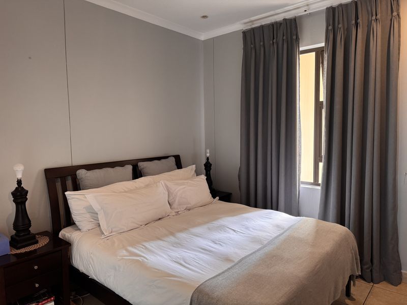 A well-maintained bedroom featuring neutral wall tones, tiled flooring, and recessed ceiling lighting, providing a comfortable and functional living space.