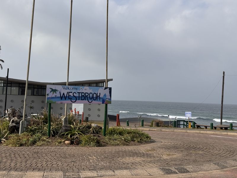A view of the Westbrook area entrance featuring a paved roundabout, signage, and coastal ocean views in the background.