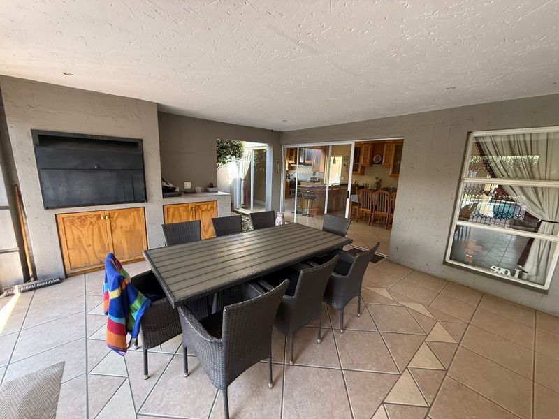 Covered patio area featuring a built-in braai, tiled flooring, and direct access to the interior living space through sliding glass doors.