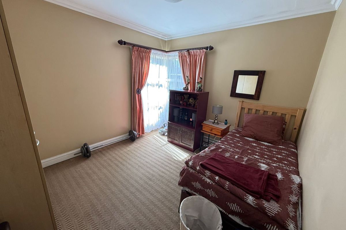 A functional bedroom featuring neutral wall tones, carpeted flooring, and decorative cornice detailing, providing a comfortable and well-proportioned living space.