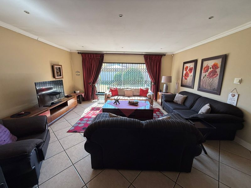 Spacious living room featuring tiled flooring, recessed lighting, and a large sliding glass door with security gate leading to the exterior.