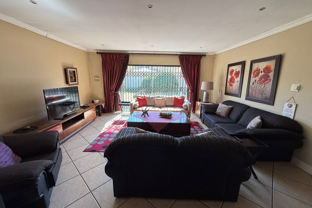 Spacious living room featuring tiled flooring, recessed lighting, and a large sliding glass door with security gate leading to the exterior.