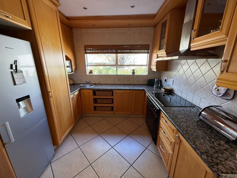 A functional kitchen featuring wooden cabinetry, granite countertops, ceramic tile backsplash, and built-in appliances, offering a classic layout with ample storage space.