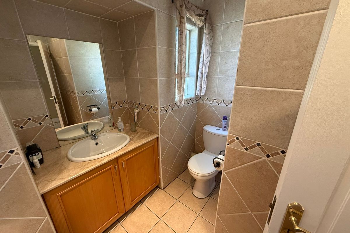 A functional bathroom featuring a vanity cabinet with a basin, tiled walls with decorative accents, and a standard toilet.