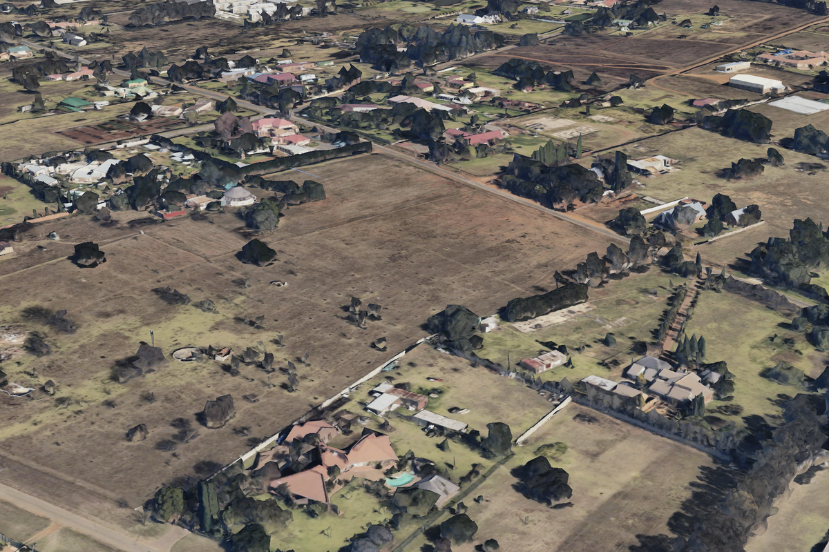 An aerial view of a residential area featuring large vacant land plots and surrounding established properties.