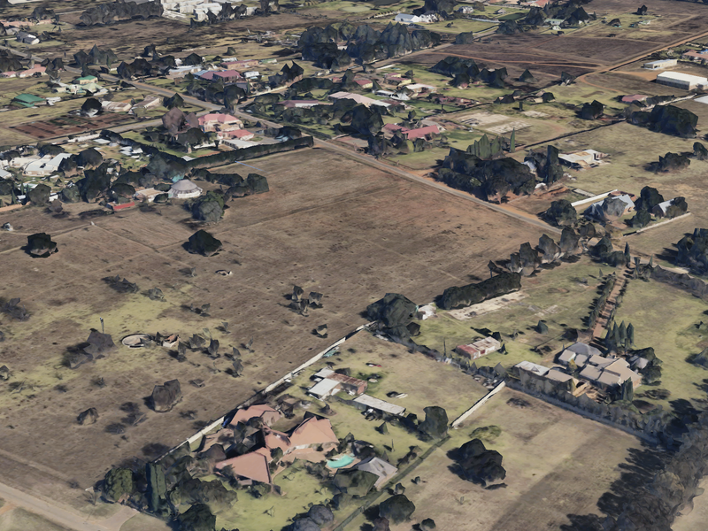 An aerial view of a residential area featuring large vacant land plots and surrounding established properties.