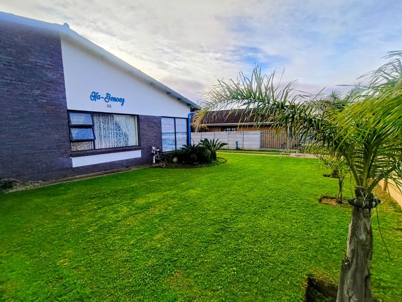A well-maintained rear garden featuring a spacious lawn, brick exterior wall, and secure precast concrete boundary fencing.