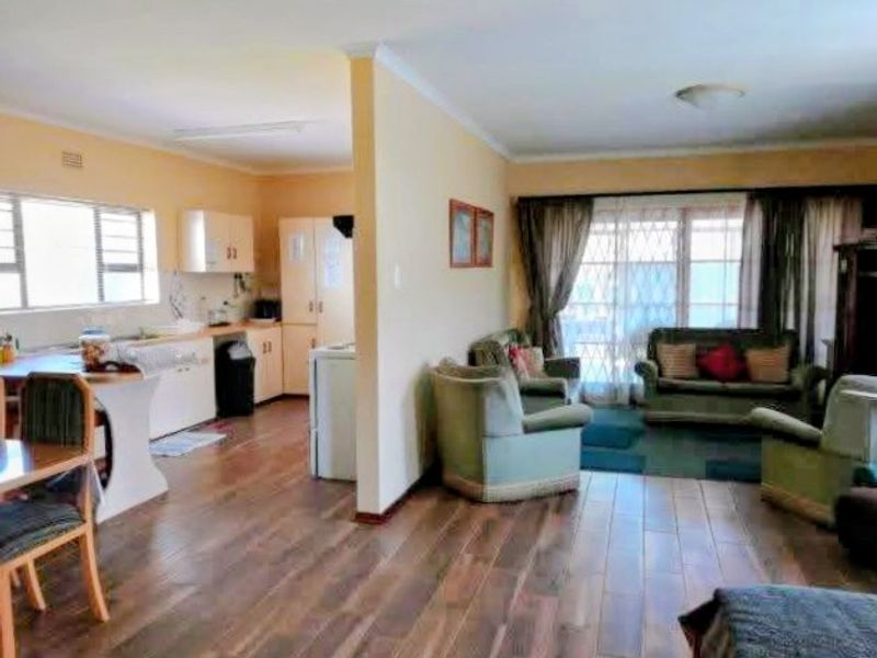 Open-plan living and kitchen area featuring laminate flooring, built-in cabinetry, and access to the exterior through a sliding door with security gate.