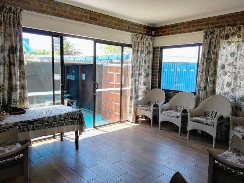 A living area featuring exposed brick walls, tiled flooring, and large sliding glass doors providing direct access to the outdoor pool area.