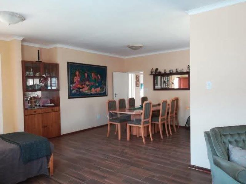 Spacious dining area featuring laminate flooring, built-in wooden cabinetry, and neutral wall finishes, providing a functional space for family meals and entertaining.