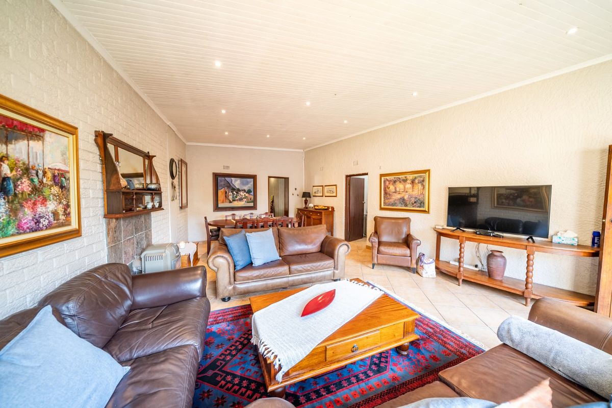 Spacious living room featuring tiled flooring, a brick feature wall with a fireplace, and a tongue and groove ceiling with recessed lighting.