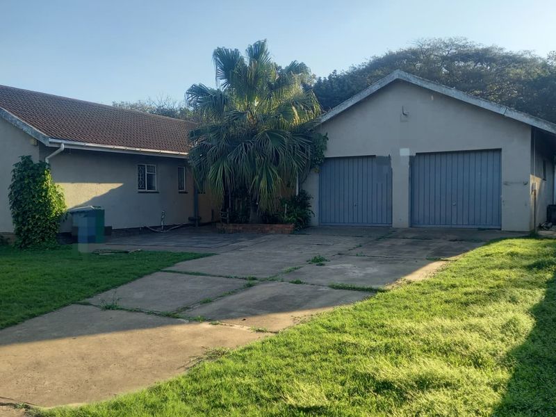 Front exterior view of the property featuring a double garage, concrete driveway, and established garden area.