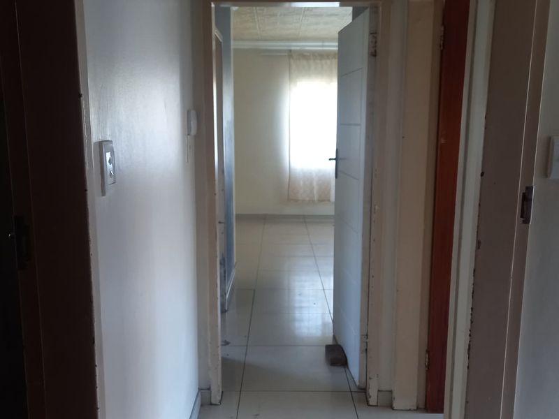 A functional hallway with tiled flooring connecting multiple rooms, featuring neutral walls and standard internal door frames.