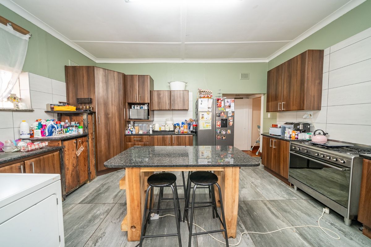 A functional kitchen featuring dark wood-look cabinetry, a central granite-topped island, and a gas stove, offering a practical layout for daily cooking.