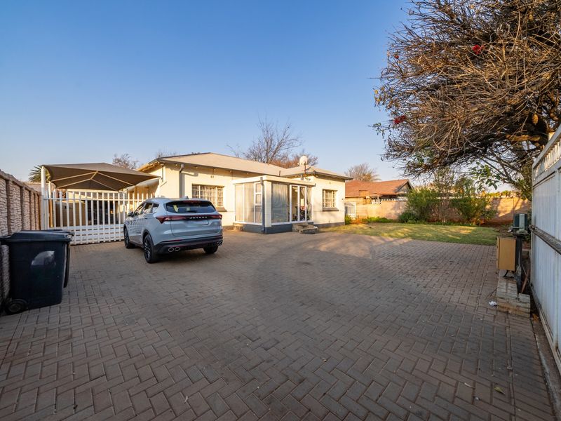 Front exterior view featuring a paved driveway, carport, and enclosed patio area, providing ample parking space and secure access to the property.
