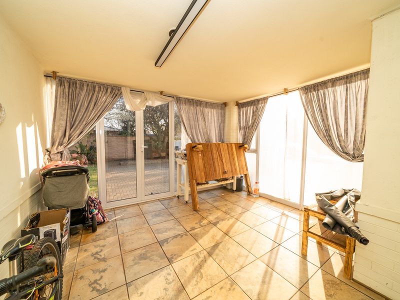 Enclosed patio area featuring tiled flooring and large glass sliding doors providing access to the rear garden.