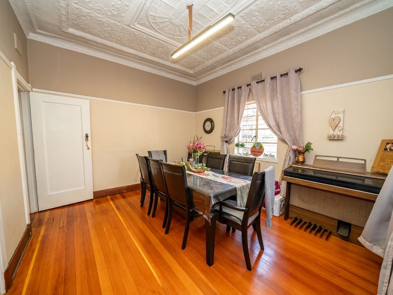 Dining room featuring original pressed metal ceilings, polished timber flooring, and a picture rail, offering a classic character aesthetic.