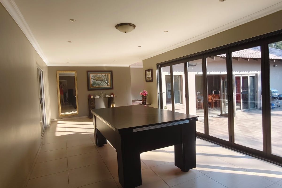 Spacious living area featuring large aluminium sliding doors that open onto an outdoor patio, complemented by tiled flooring and recessed lighting.
