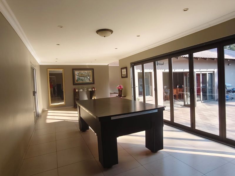 Spacious living area featuring large aluminium sliding doors that open onto an outdoor patio, complemented by tiled flooring and recessed lighting.