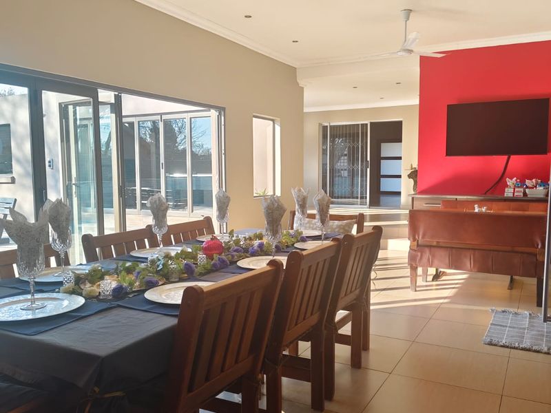 Spacious open-plan dining and living area featuring tiled floors, ceiling fans, and large sliding glass doors that provide seamless access to the outdoor space.