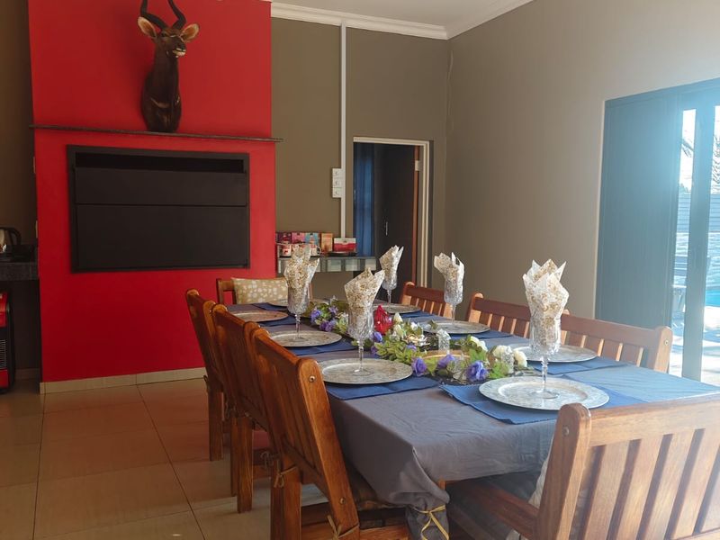 Dining room featuring a built-in fireplace with a red accent wall, tiled flooring, and direct access to the outdoor area via sliding glass doors.