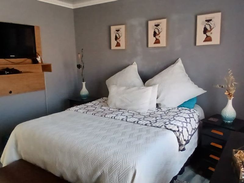 A cozy bedroom featuring grey painted walls and a built-in wall-mounted media unit.