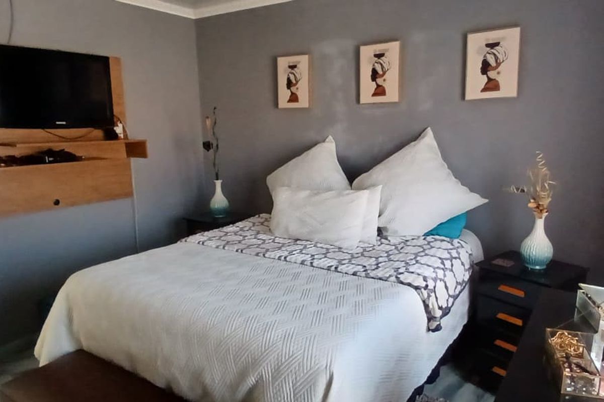 A cozy bedroom featuring grey painted walls and a built-in wall-mounted media unit.