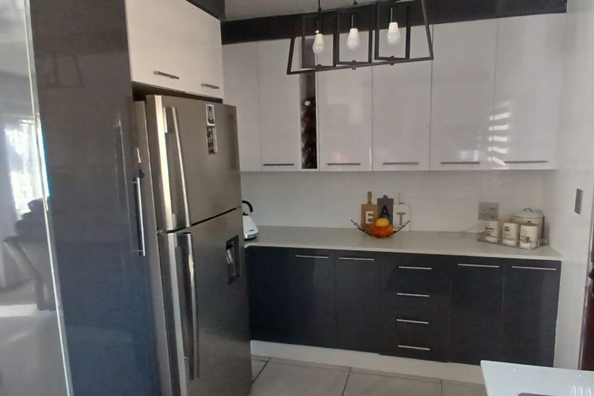 Modern kitchen featuring high-gloss cabinetry, stone countertops, and contemporary pendant lighting, offering a clean and functional workspace.