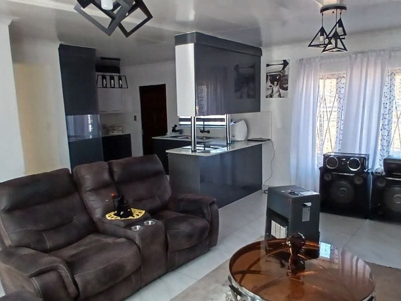 An open-plan living and kitchen area featuring modern grey cabinetry, a central kitchen island, and tiled flooring throughout.