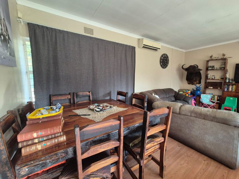 Open plan living and dining area featuring laminate flooring and a wall-mounted air conditioning unit.