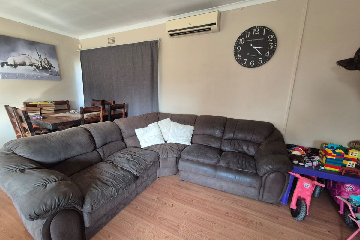 A living room featuring laminate flooring, a wall-mounted split-system air conditioner, and coved ceiling details.