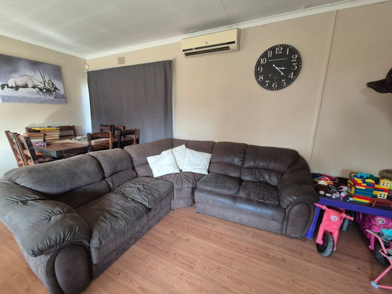 A living room featuring laminate flooring, a wall-mounted split-system air conditioner, and coved ceiling details.