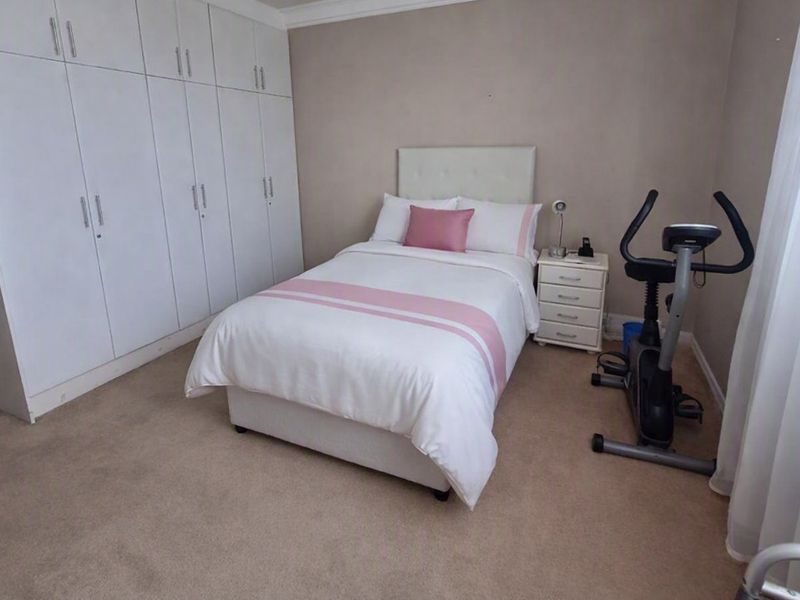 A well-proportioned bedroom featuring extensive built-in cupboard storage, neutral carpeting, and coved ceiling detailing.