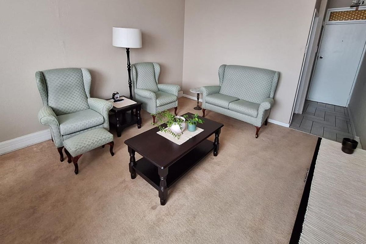 A living room area featuring neutral wall tones, carpeted flooring, and access to an internal doorway.