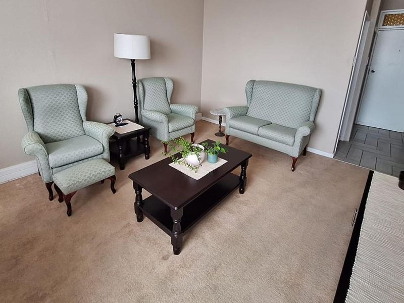 A living room area featuring neutral wall tones, carpeted flooring, and access to an internal doorway.