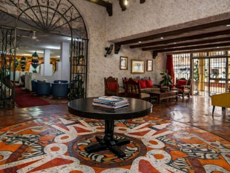 Spacious clubhouse interior featuring decorative mosaic flooring, exposed timber ceiling beams, and a distinctive wrought iron arched entryway.