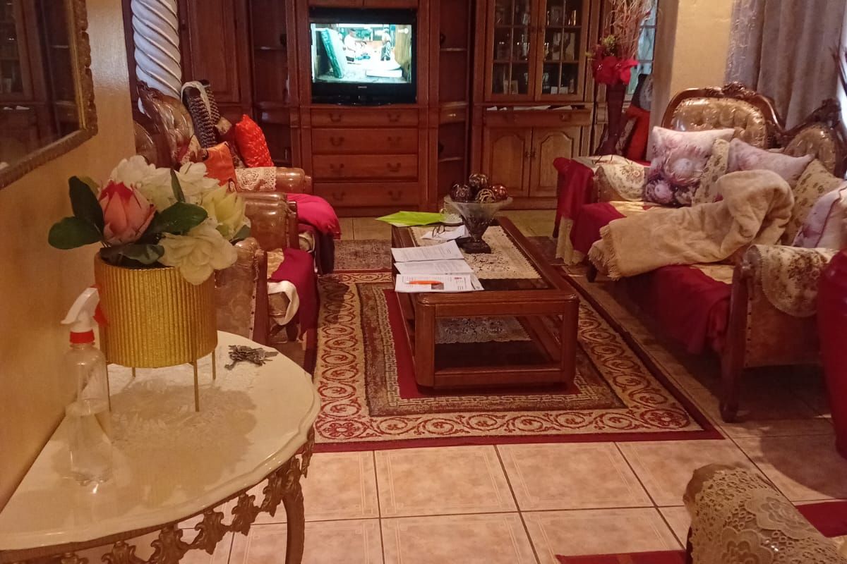 A traditional living room featuring ceramic floor tiles, decorative column detailing, and built-in wooden cabinetry with integrated shelving.