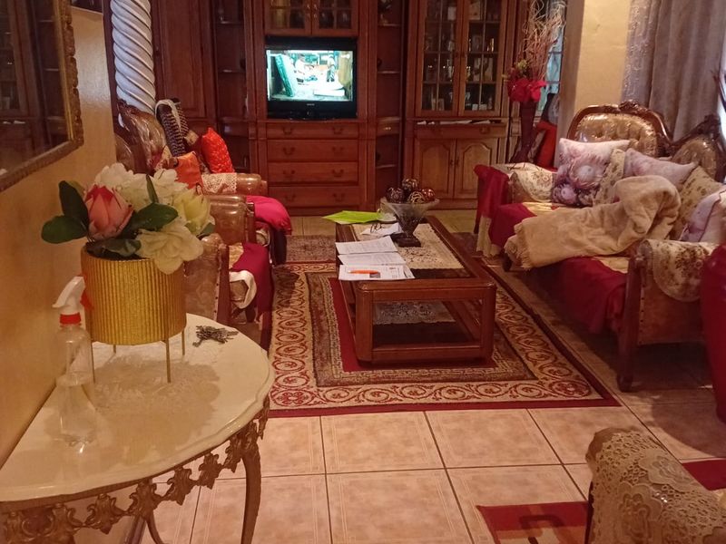 A traditional living room featuring ceramic floor tiles, decorative column detailing, and built-in wooden cabinetry with integrated shelving.