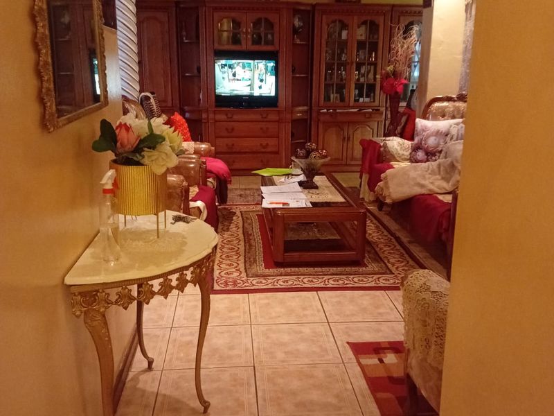 A living room featuring tiled flooring, decorative ceiling molding, and an ornate column, with built-in cabinetry providing storage and display space.