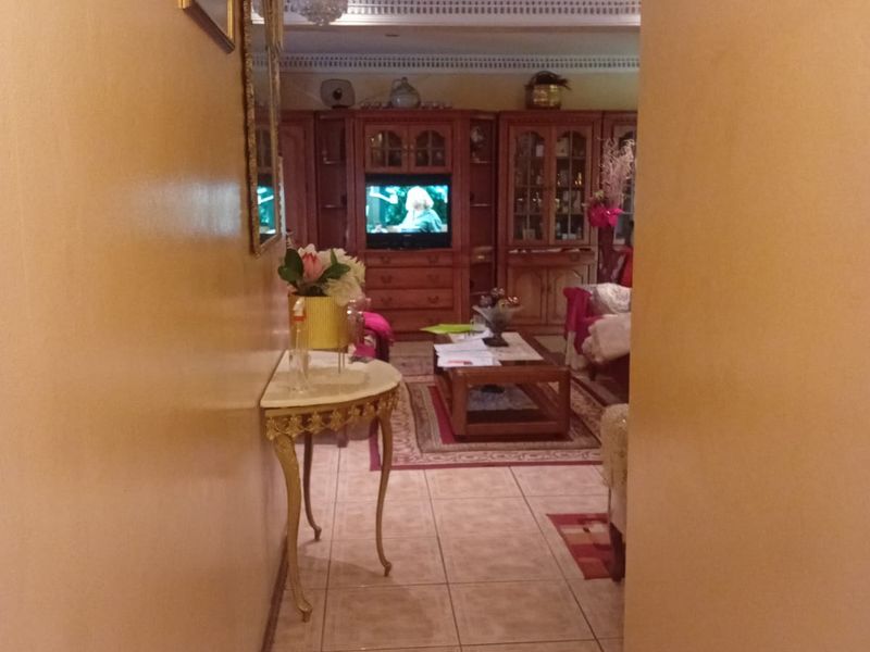 A view from a hallway into a living room featuring tiled floors, decorative ceiling details, and built-in wooden cabinetry.